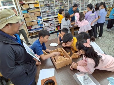 由知本自然教育中心講師帶領學童觀察國產材教具，介紹不同樹種的木紋特色。